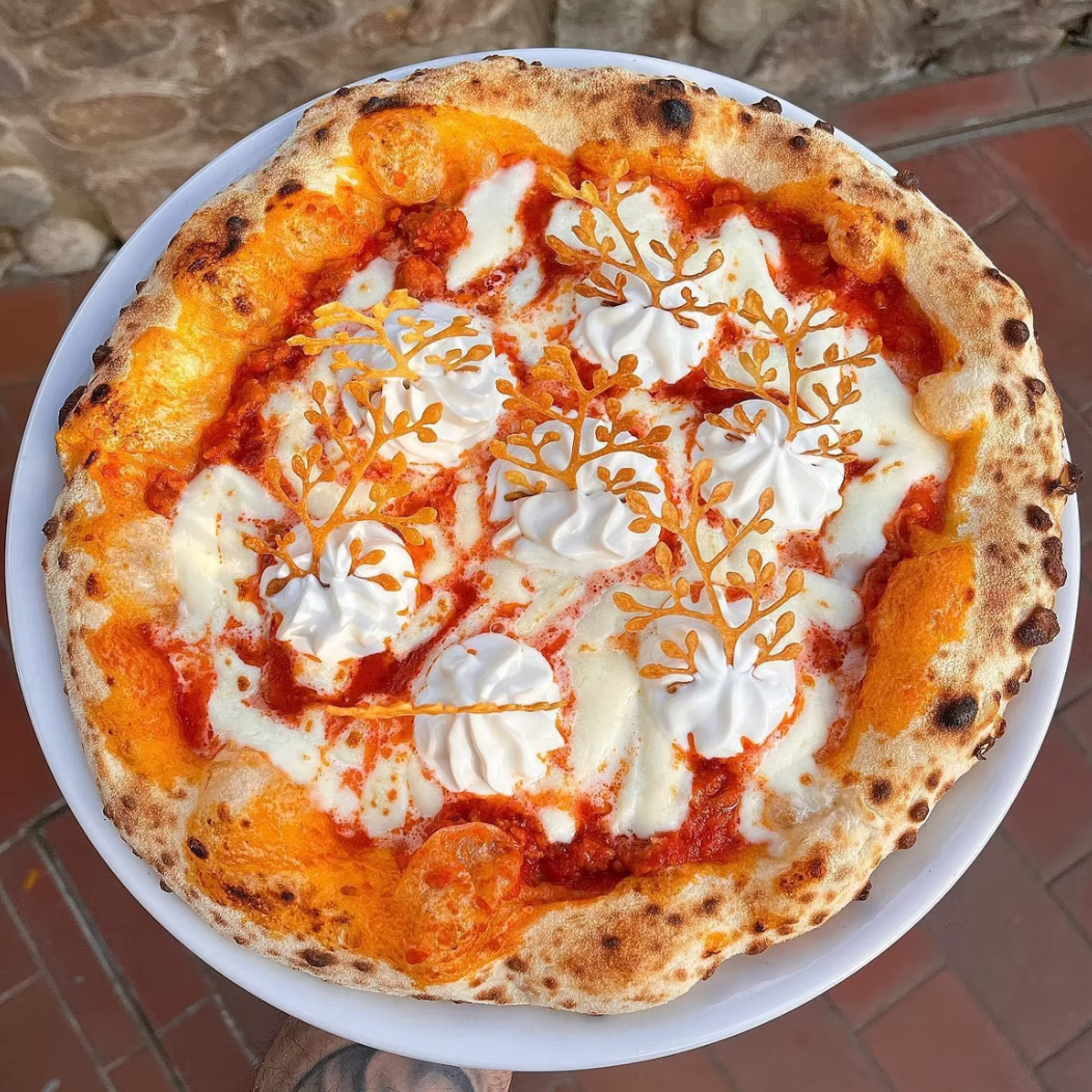 Overhead view of Neapolitan pizza with artisanal pastry decorations and cream